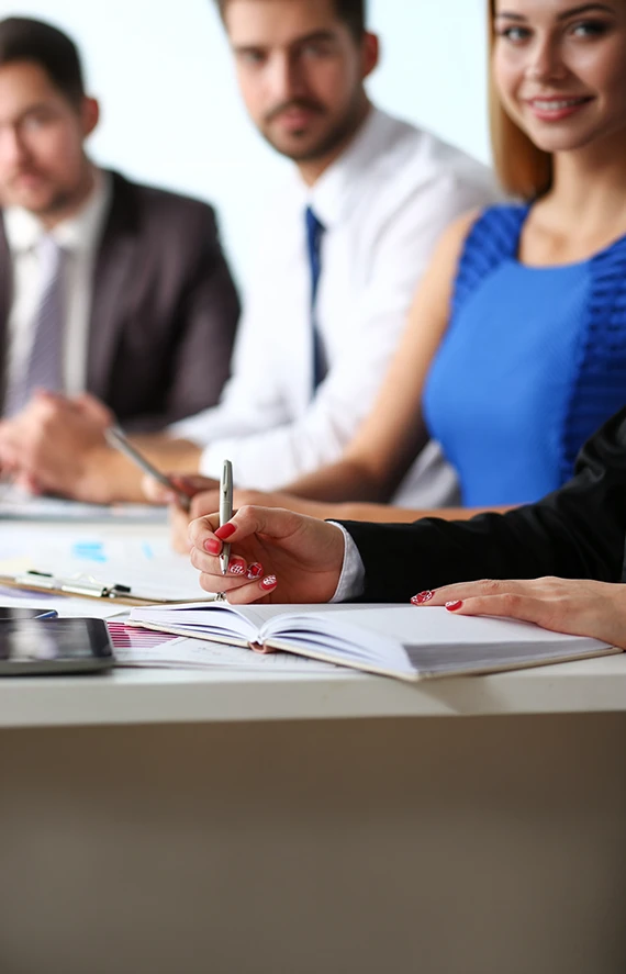 A professional advisory team sitting at a conference table taking notes, gathered to discuss and act on strategic insights derived from recent online surveys.
